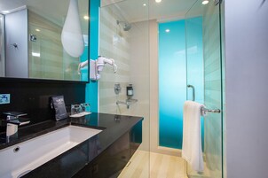 A modern bathroom with a black sink, glass shower enclosure, and a white towel hanging on the glass door.