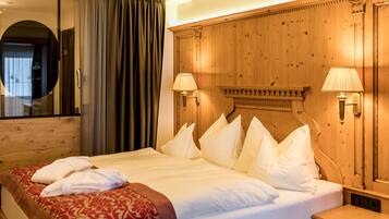 A hotel room with a large bed, two bedside lamps, a wooden headboard, and a mirror.