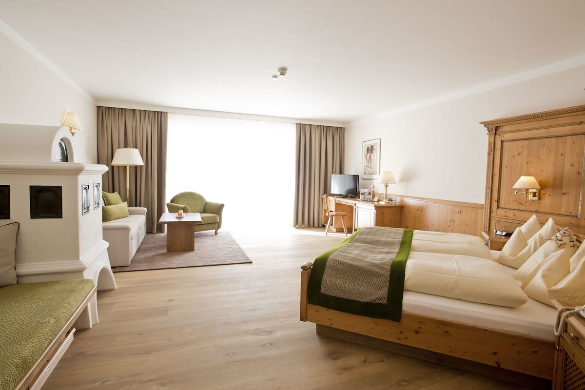 A hotel room with a bed, a sofa, a desk, a television, and a wooden cabinet.