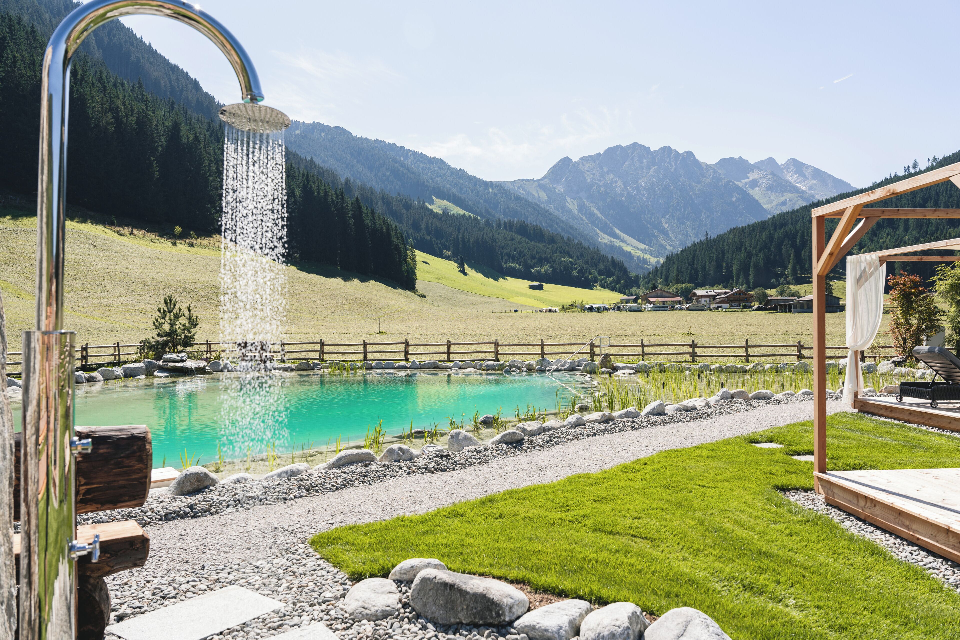 A mountain landscape with a clear pool, a wooden deck, and a gazebo.