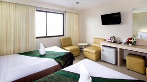A hotel room with two beds, a desk, a chair, a small table, a TV, and a minibar. - Hat Yai Rama Hotel (Hat Yai)