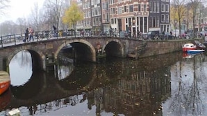 Un canal con un puente de piedra, edificios de arquitectura tradicional y barcos.