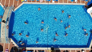 A large rectangular swimming pool with multiple lanes, surrounded by a tiled deck and a lifeguard stand.
