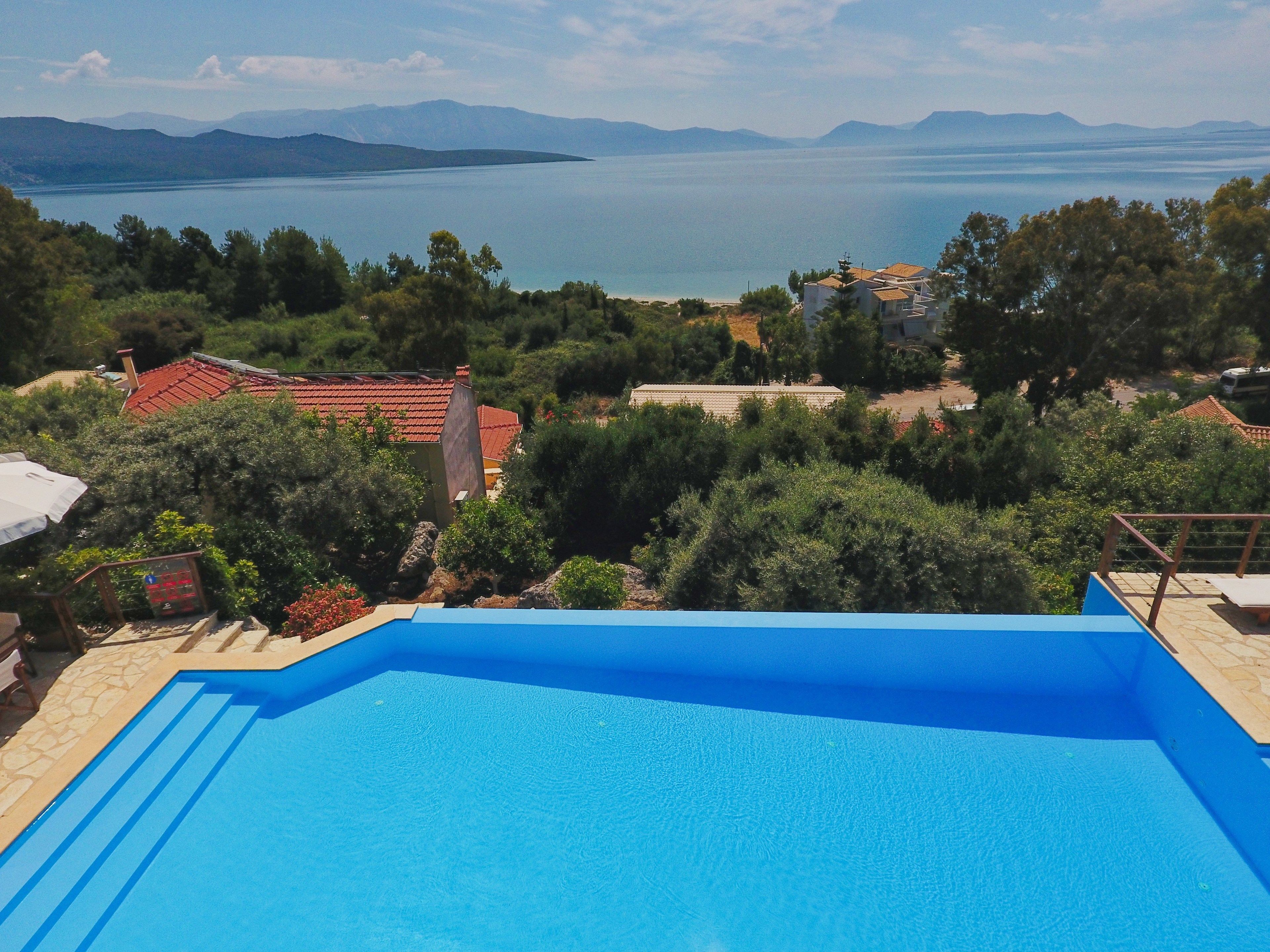 A swimming pool with a view of a lake and mountains in the background.