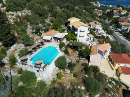 Vista aérea de una propiedad costera con piscina, varias construcciones y abundante vegetación.