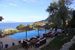 A poolside area with lounge chairs and umbrellas, overlooking a body of water and a mountainous landscape. - La Casa Di Nonna Anna (Lefkada)