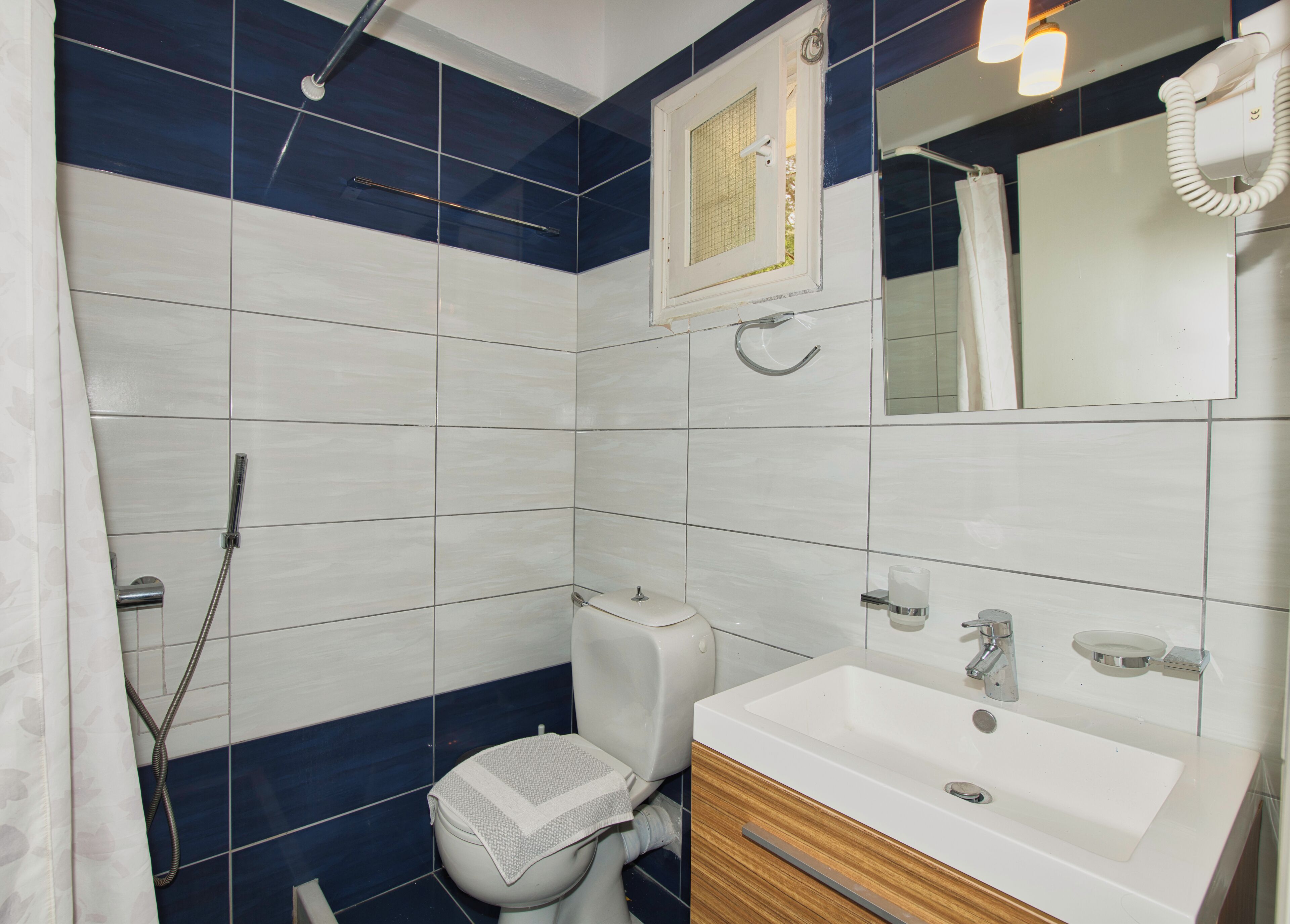 Un baño con ducha, inodoro, lavamanos y espejo.