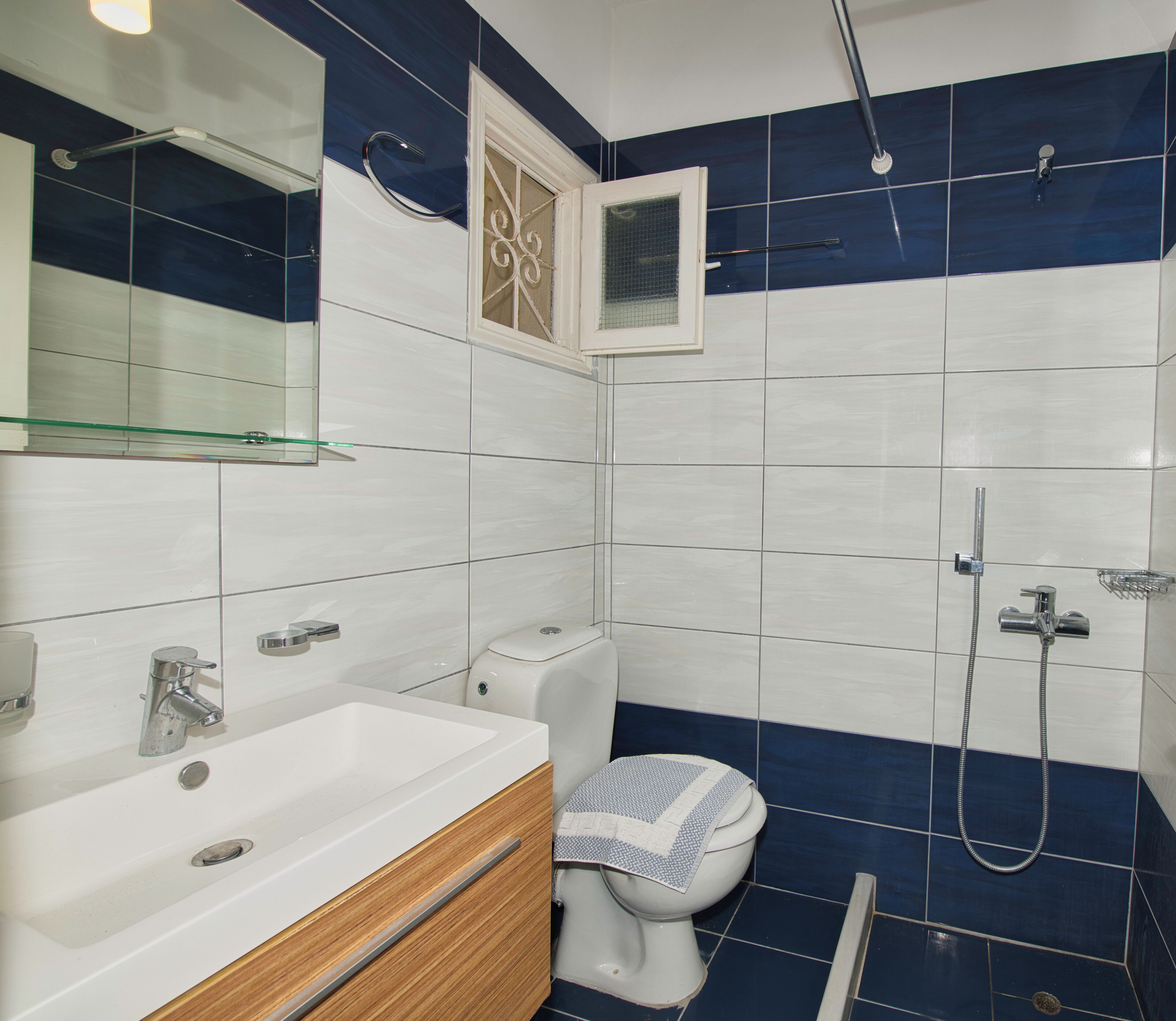 A bathroom with a white sink, a mirror, a toilet, and a shower area.