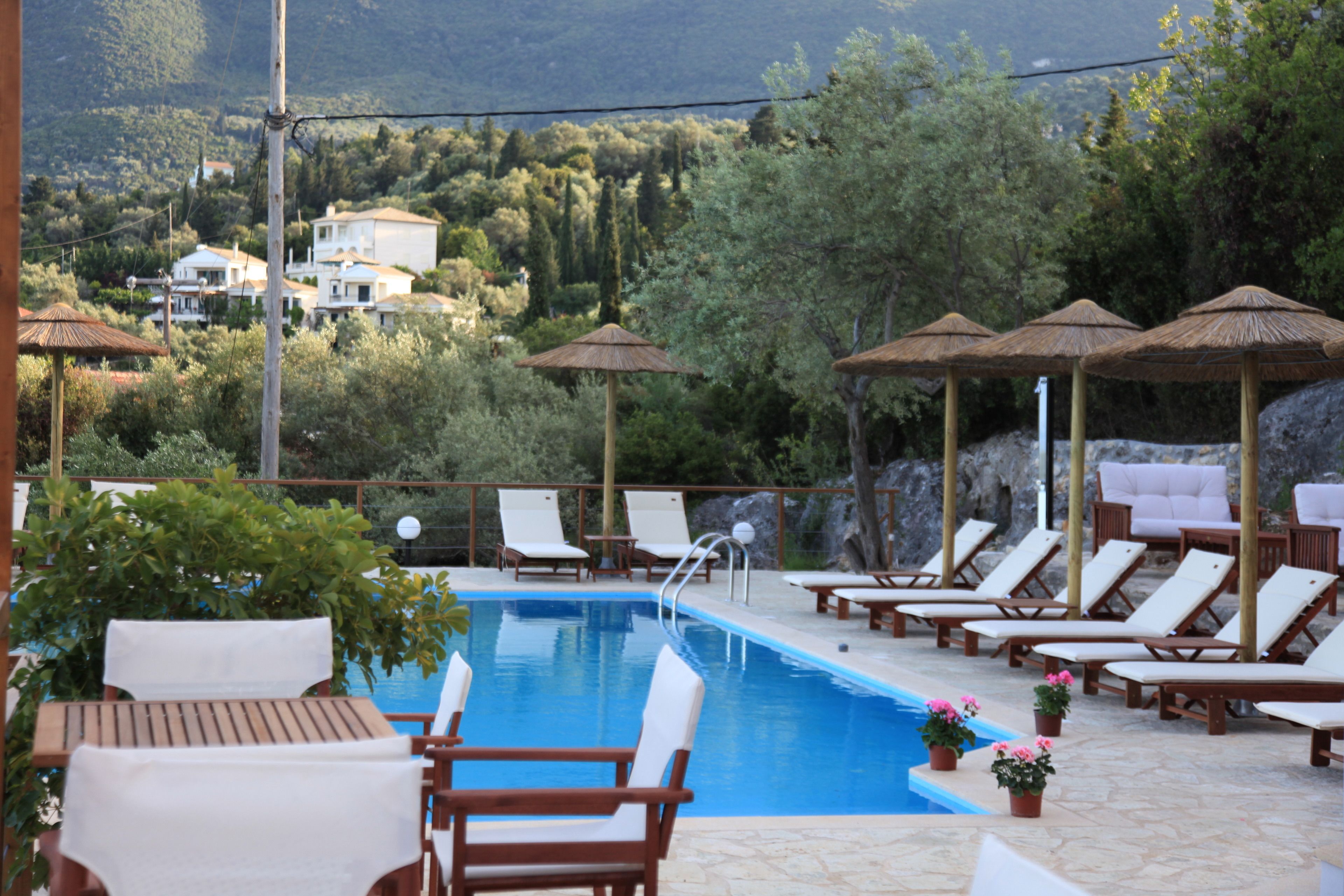 Un área junto a la piscina con sillones de descanso, sombrillas y vistas del paisaje circundante.