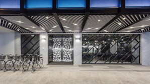 A modern building entrance with a glass facade, a stone wall, and a bike parking area. - The Cloud Hotel Taichung (Taichung)
