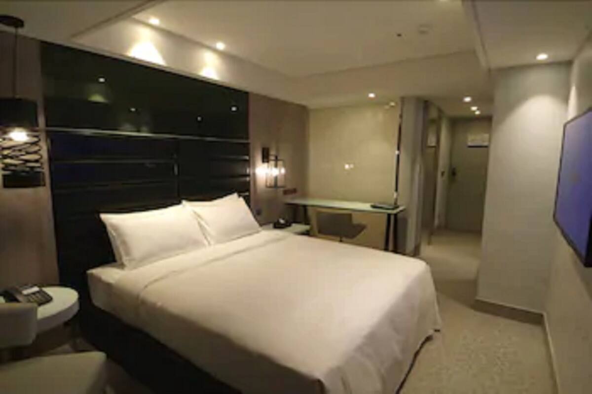 Quarto de hotel moderno com uma cama grande, uma escrivaninha e um espaço de estar.