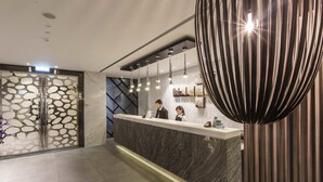 A modern reception desk with a marble top, a glass partition with a unique pattern, and a contemporary light fixture. - The Cloud Hotel Taichung (Taichung)