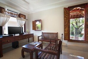 A living room with a TV, wooden furniture, and a decorative mirror.