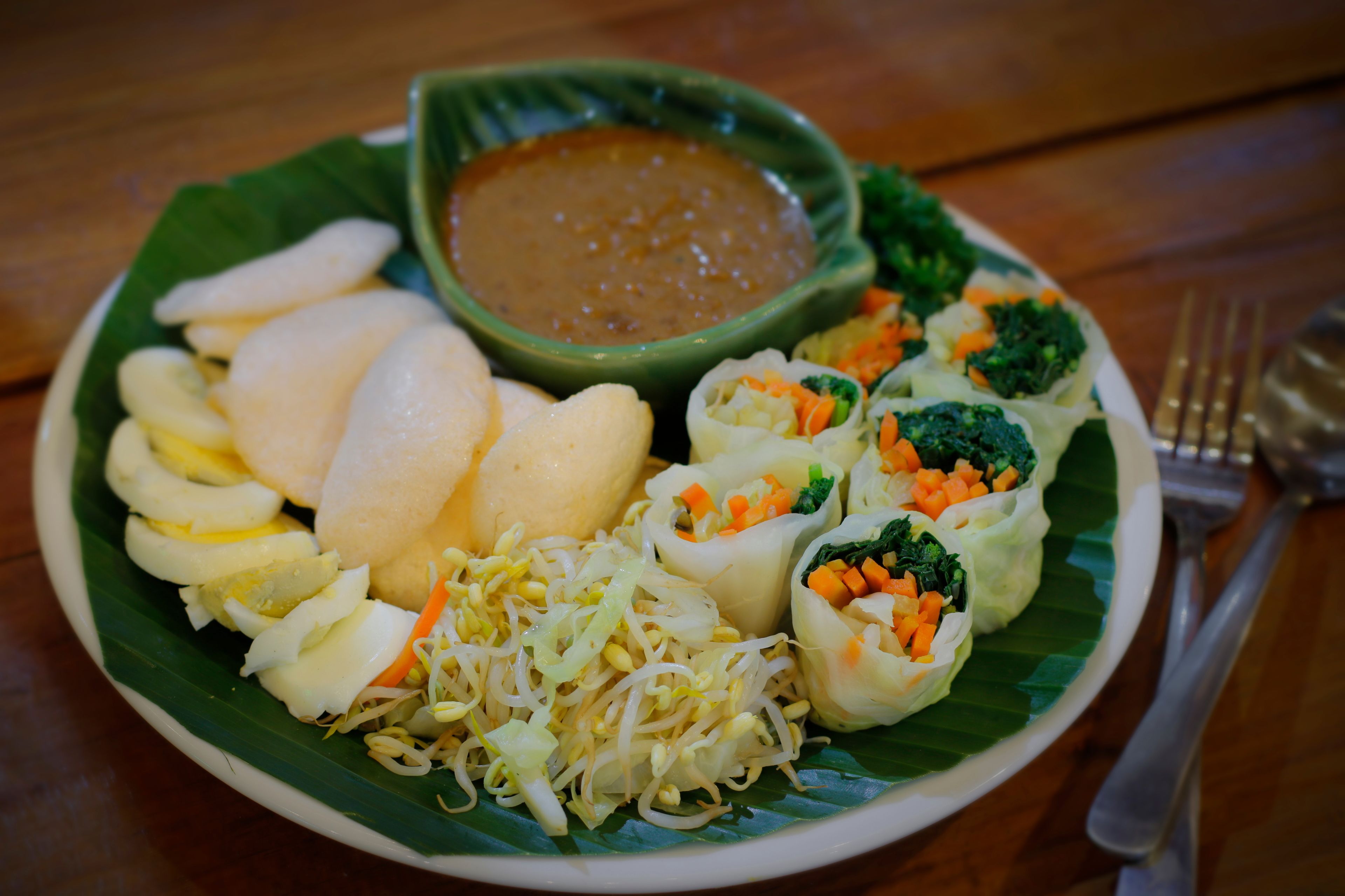 A plate of food including boiled eggs, spring rolls, and a bowl of sauce.