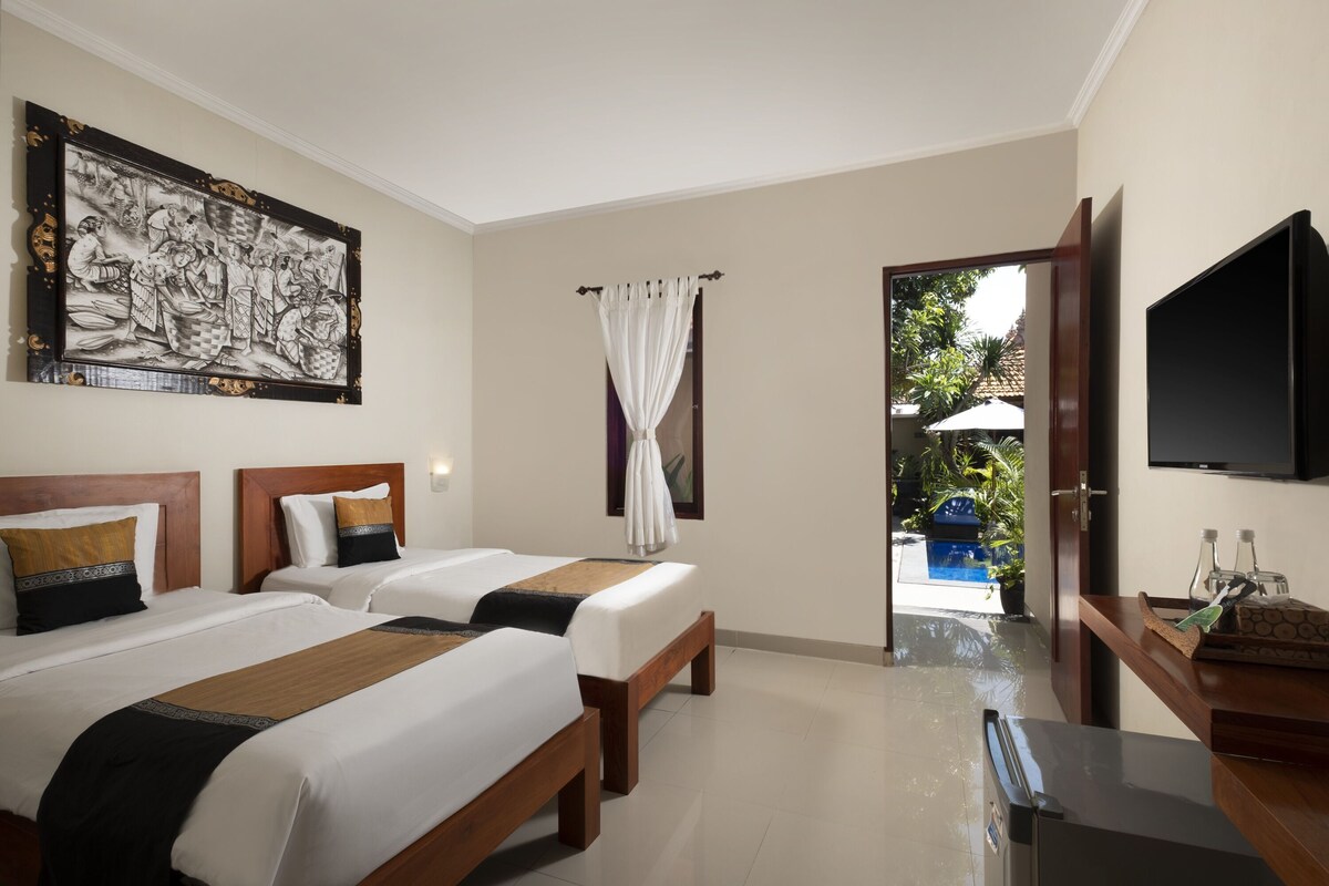 A hotel room with two beds, a TV, a painting, and a view of an outdoor pool.