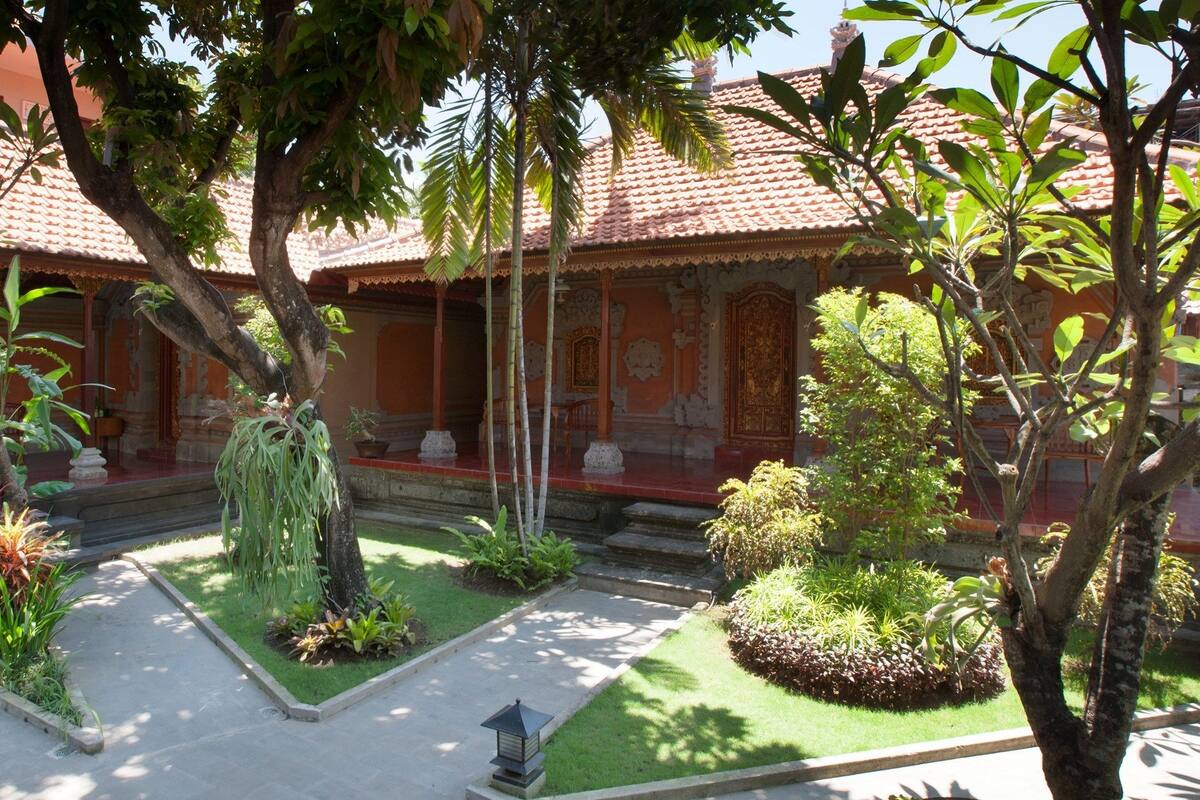 A traditional building with a tiled roof, surrounded by lush greenery and a well-maintained garden.