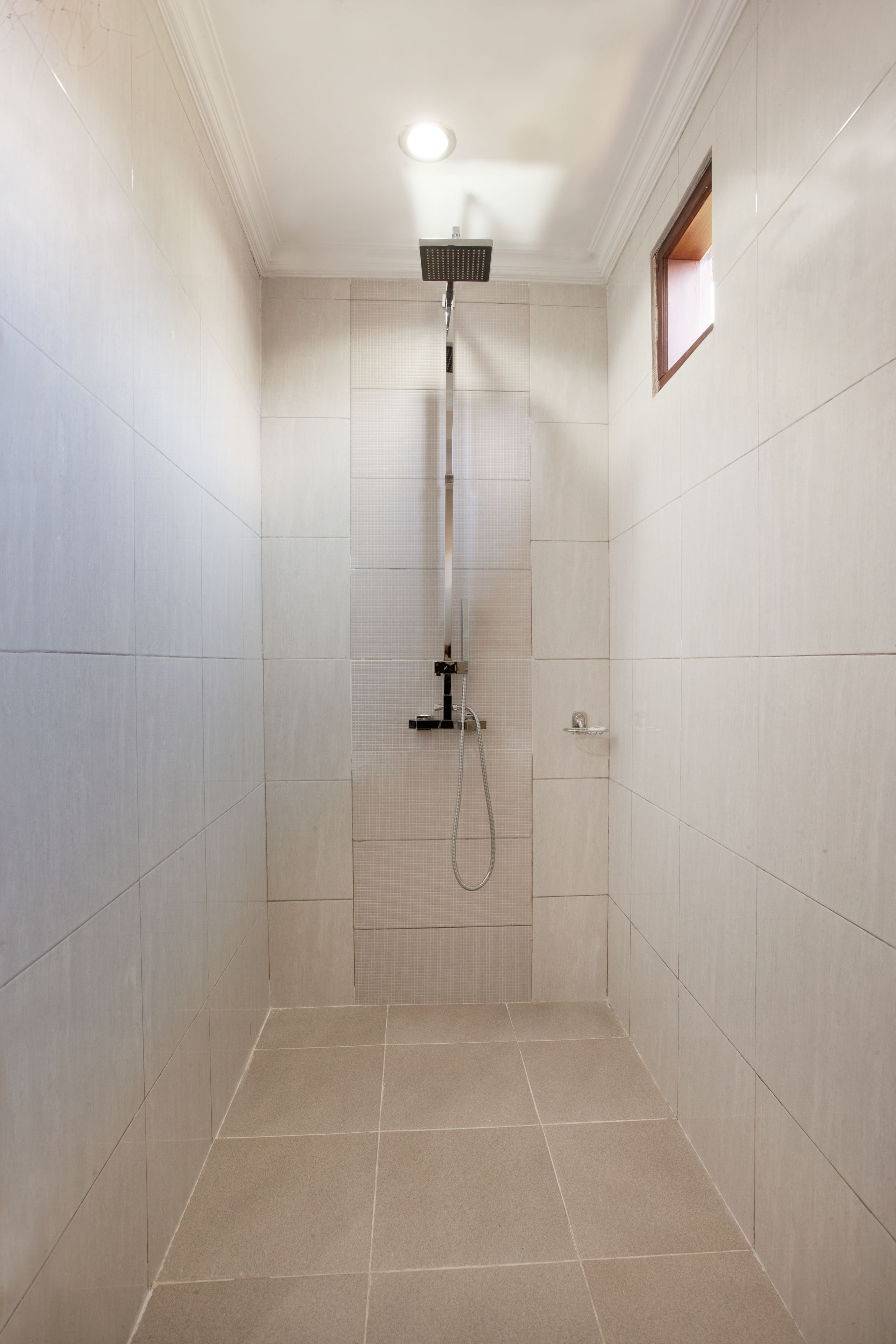 Un baño pequeño con azulejos, una lámpara en el techo y una ventana.