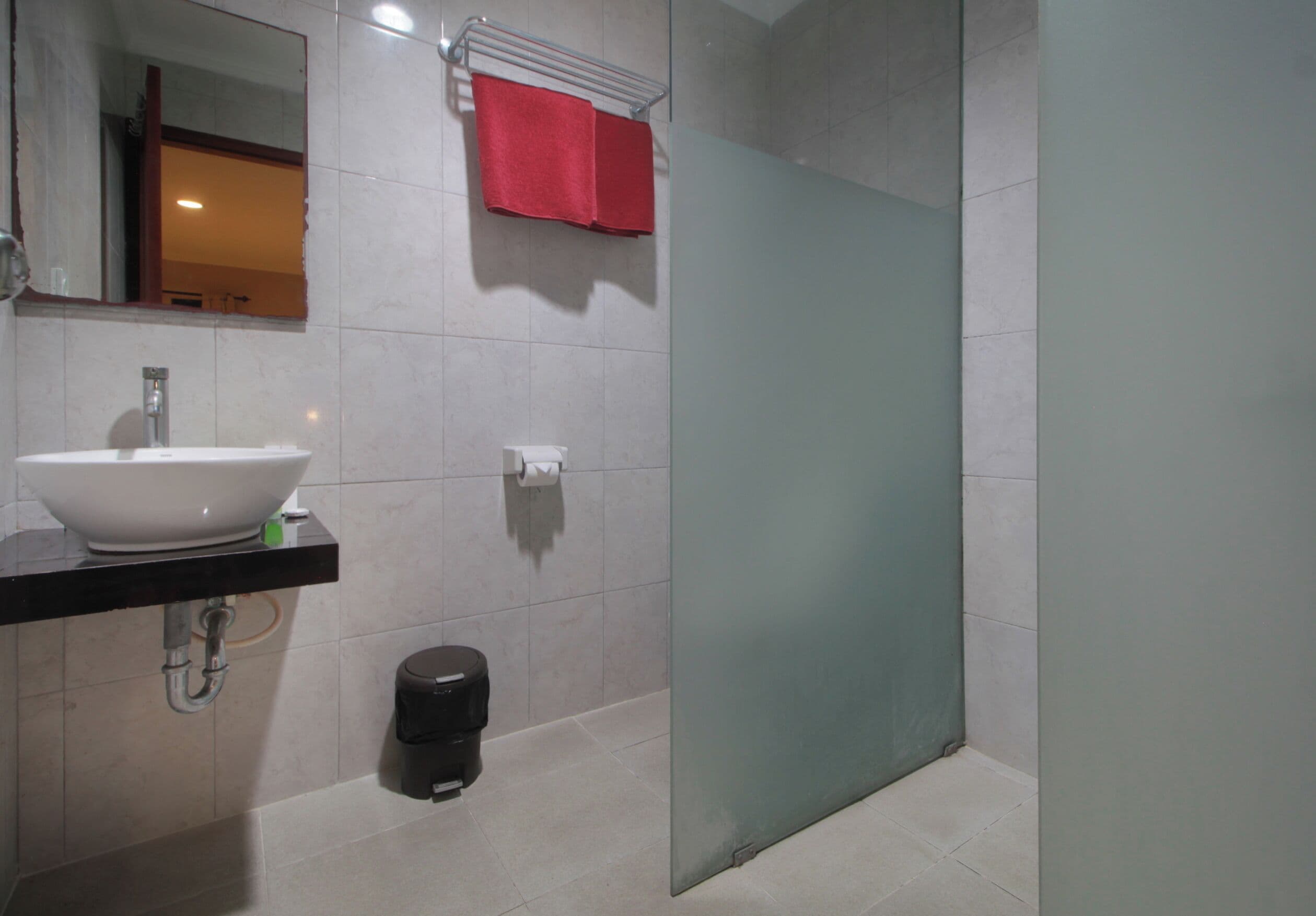 A modern bathroom with a white sink, mirror, and a glass shower door.