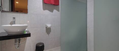 A modern bathroom with a white sink, mirror, and a glass shower door.