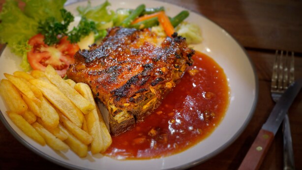 A plate with grilled meat, fries, and vegetables. - NESA Sanur Bali (Denpasar)
