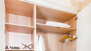 Um closet espaçoso com várias prateleiras, um cabideiro e um pequeno espaço para sentar.