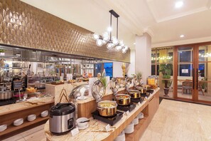 Un espace buffet avec différents postes de service proposant divers plats, notamment un cuiseur à riz et un appareil à fondue.