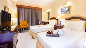 Quarto de hotel com duas camas, televisão, escrivaninha e uma cadeira.