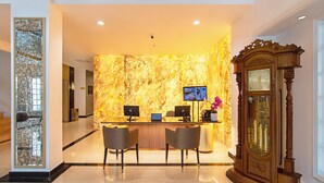 Uma área de recepção com parede de mármore, um armário de madeira e dois monitores de computador.