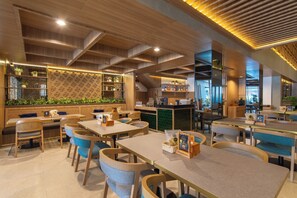 Een restaurant met houten balken in het plafond, zitplaatsen met blauwe kussens en een bar met planken.