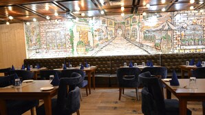 A restaurant with booths and tables, a mural on the wall, and wooden flooring. - Hotel Solitaire Chandigarh (Chandigarh)
