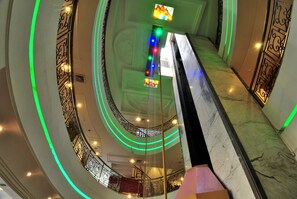 Un interior de varios niveles con una escalera espiral central, barandillas decorativas y una serie de luces a lo largo de las paredes.