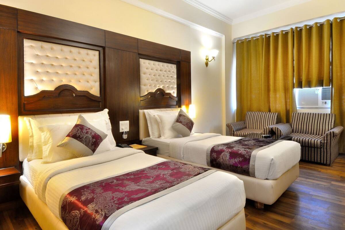 A hotel room with two beds, a sofa, and a chair.