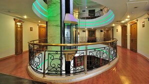 A grand, multi-level interior with a central spiral staircase, wooden flooring, and ornate metal railings. - Hotel Solitaire Chandigarh (Chandigarh)