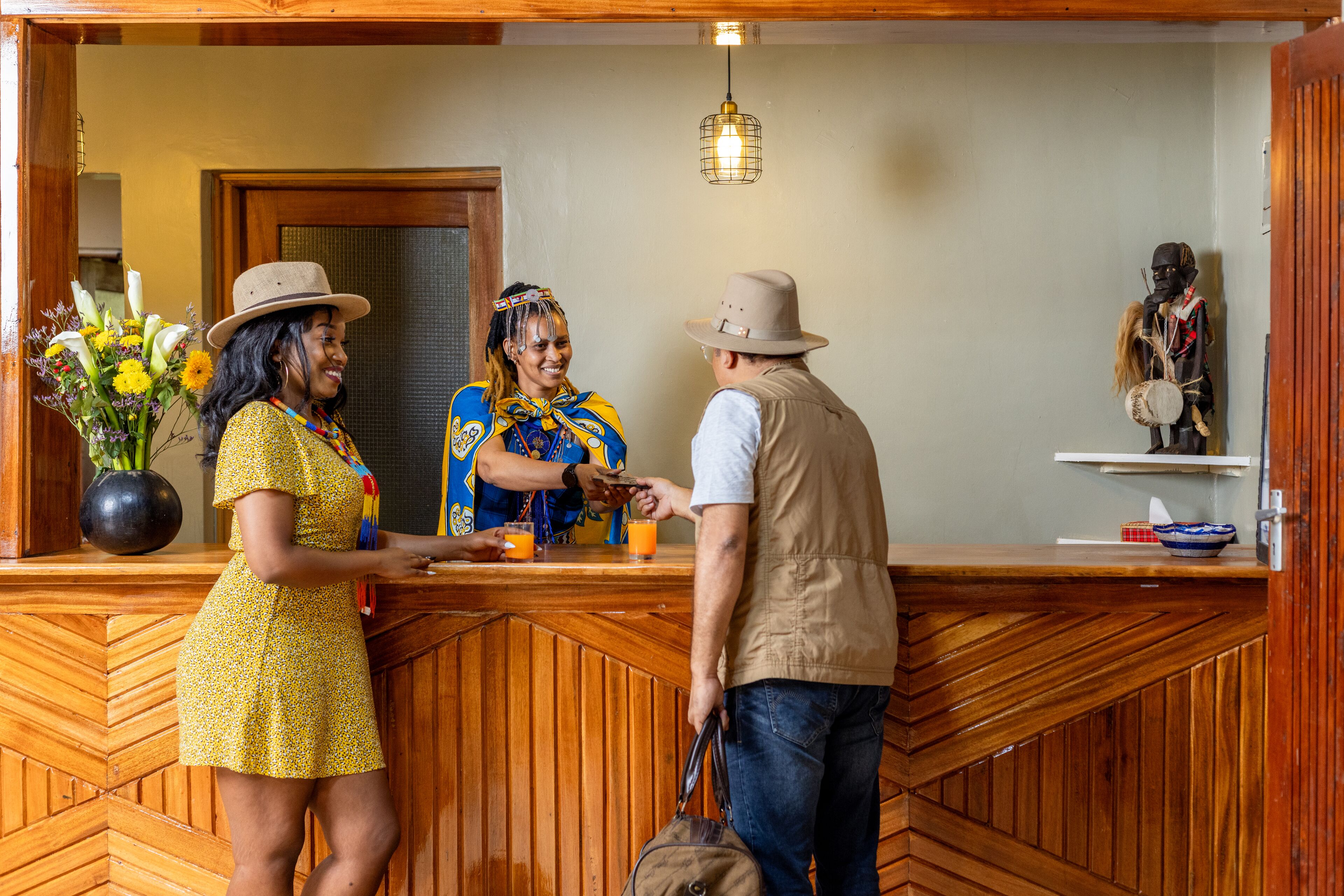 A reception area with a wooden counter, a vase of flowers, and a statue on a shelf.