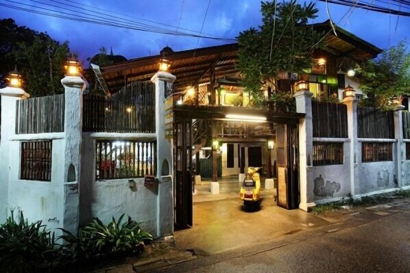 A traditional wooden house with a gated entrance, a covered porch, and a scooter parked outside. - Nai Boutique House (Chiang Mai)