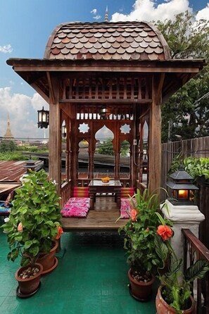 A wooden gazebo with a tiled roof, surrounded by potted plants and a green floor. - Nai Boutique House (Chiang Mai)