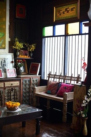 A cozy room with a wooden bench, a glass table with a bowl of fruit, and a window with vertical blinds.