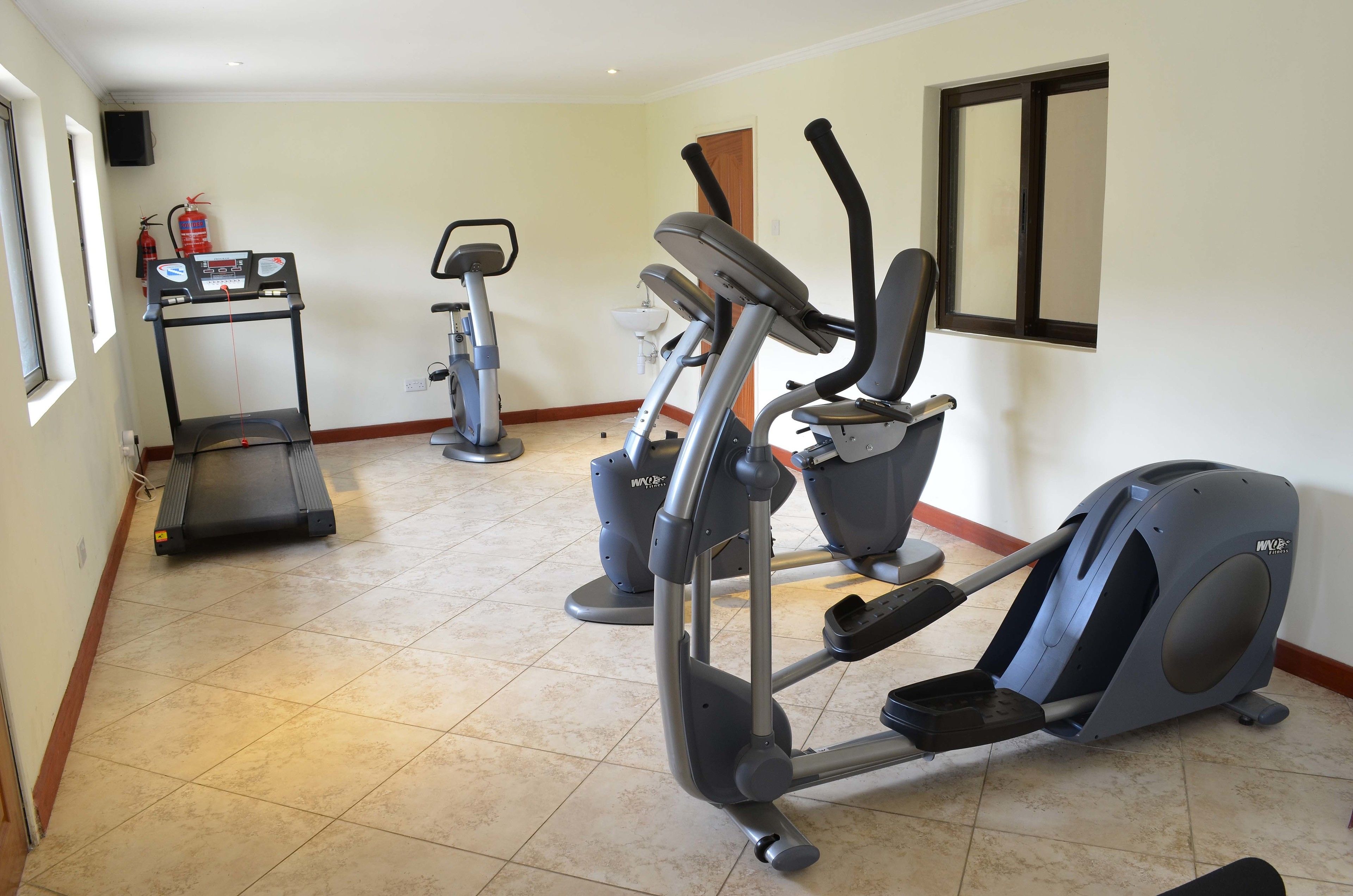 A home gym with a treadmill, elliptical, and stationary bike.
