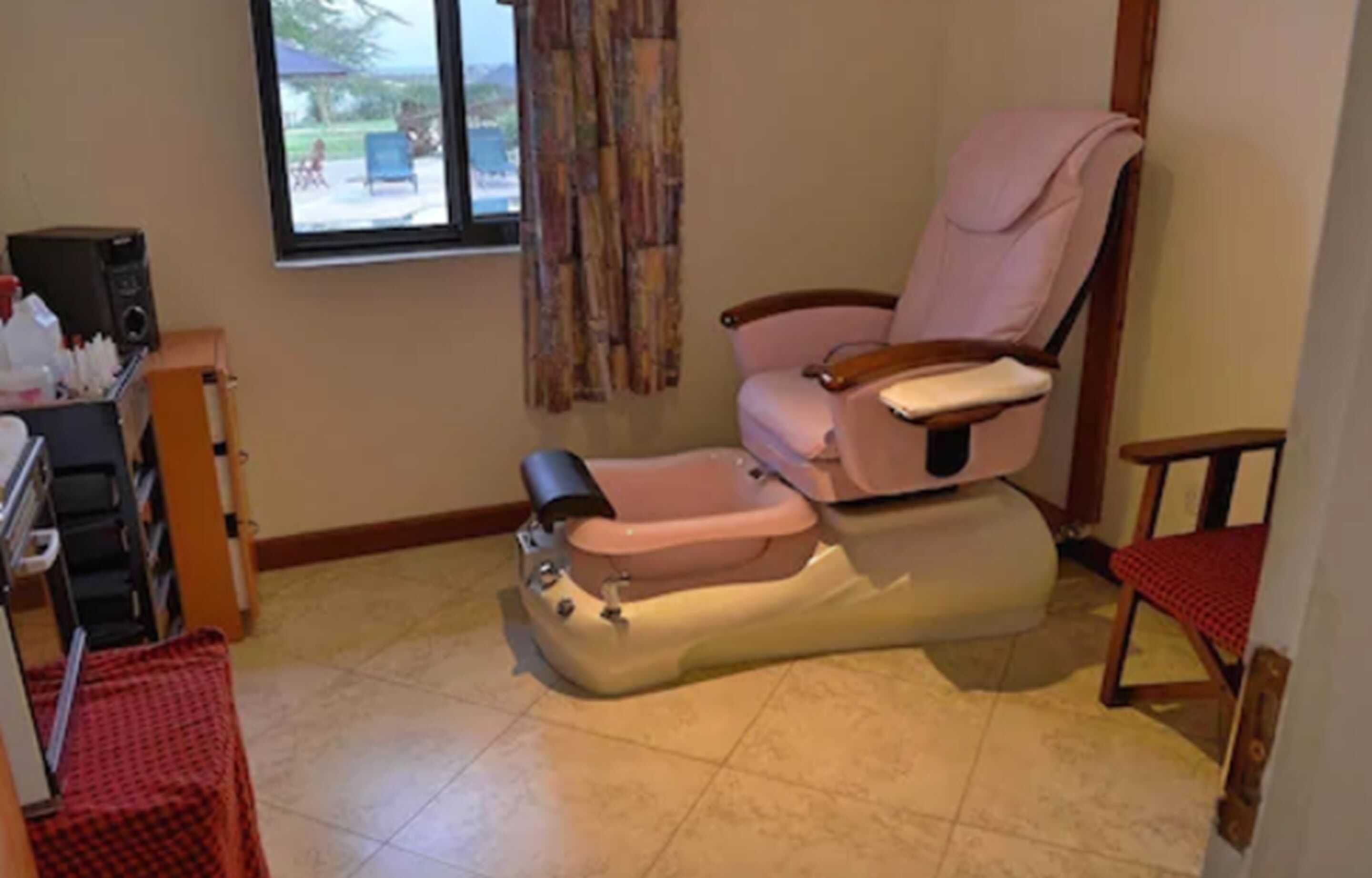 A massage chair in a room with a window, a small table, and a chair.