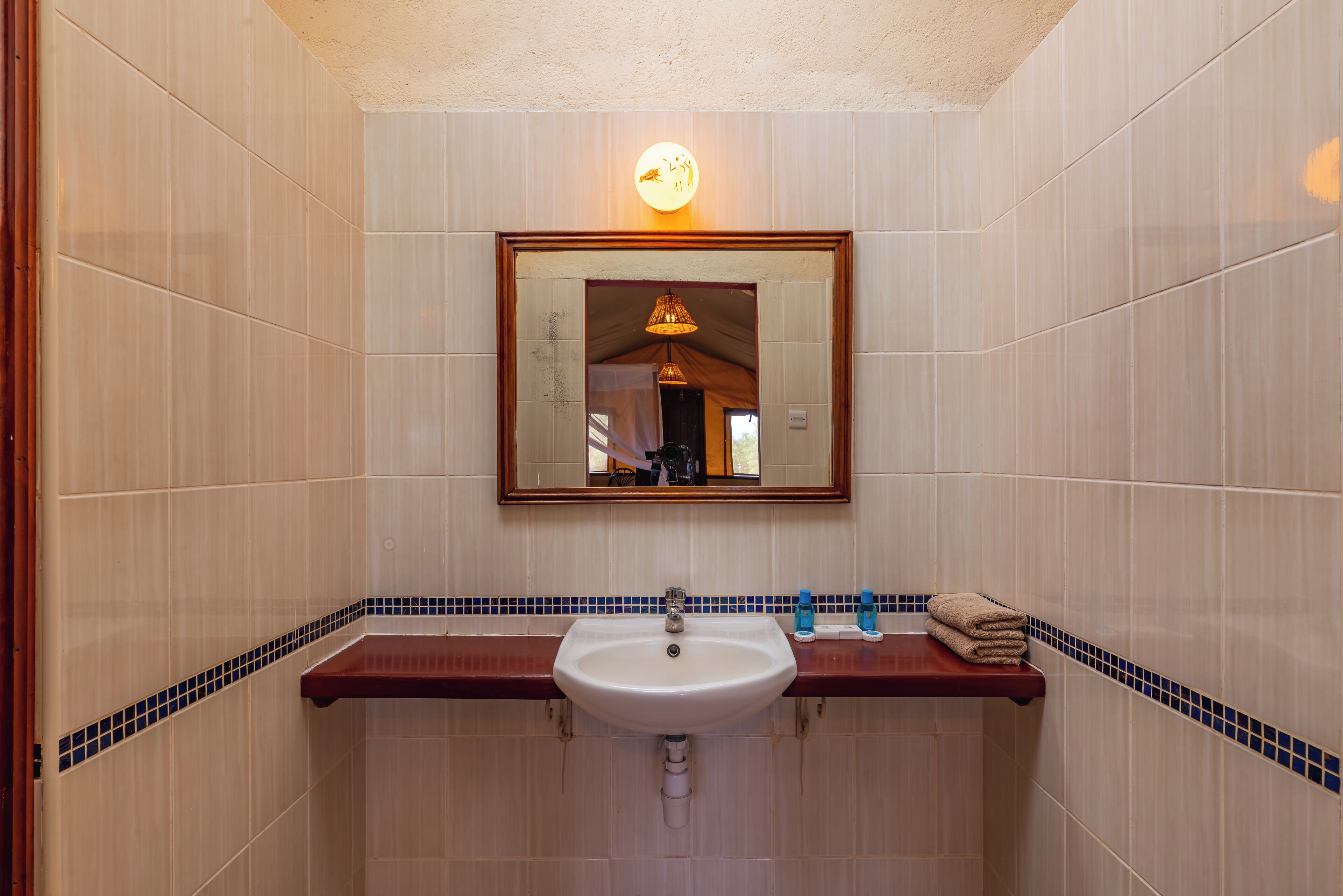 Un baño con un lavamanos blanco, una encimera de madera y un espejo encima.