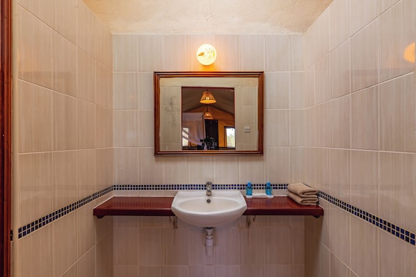 Un baño con un lavamanos blanco, una encimera de madera y un espejo encima.