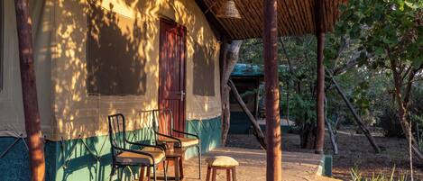Un espacio de estar al aire libre cubierto, con una mesa, sillas, un banco de madera y un colgador de luces.