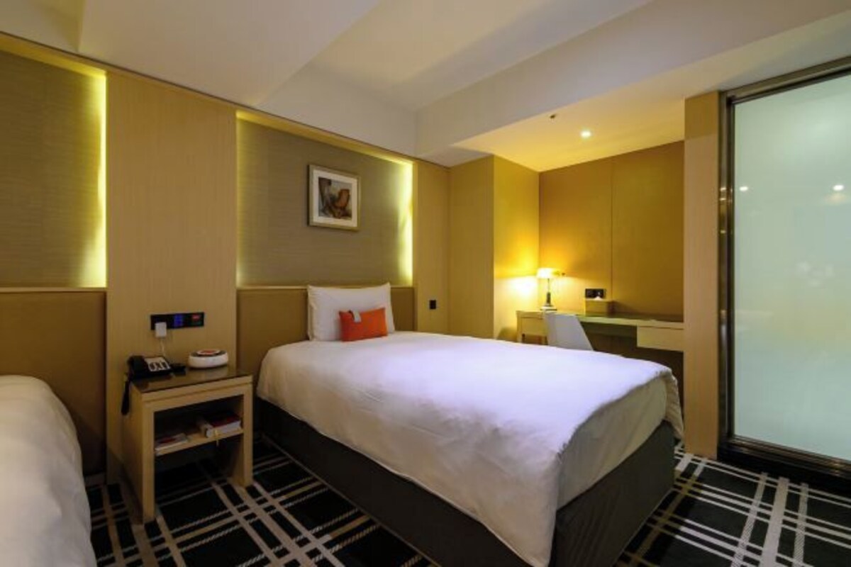 Una habitación de hotel con una cama grande, mesitas de noche, un escritorio y un espejo.