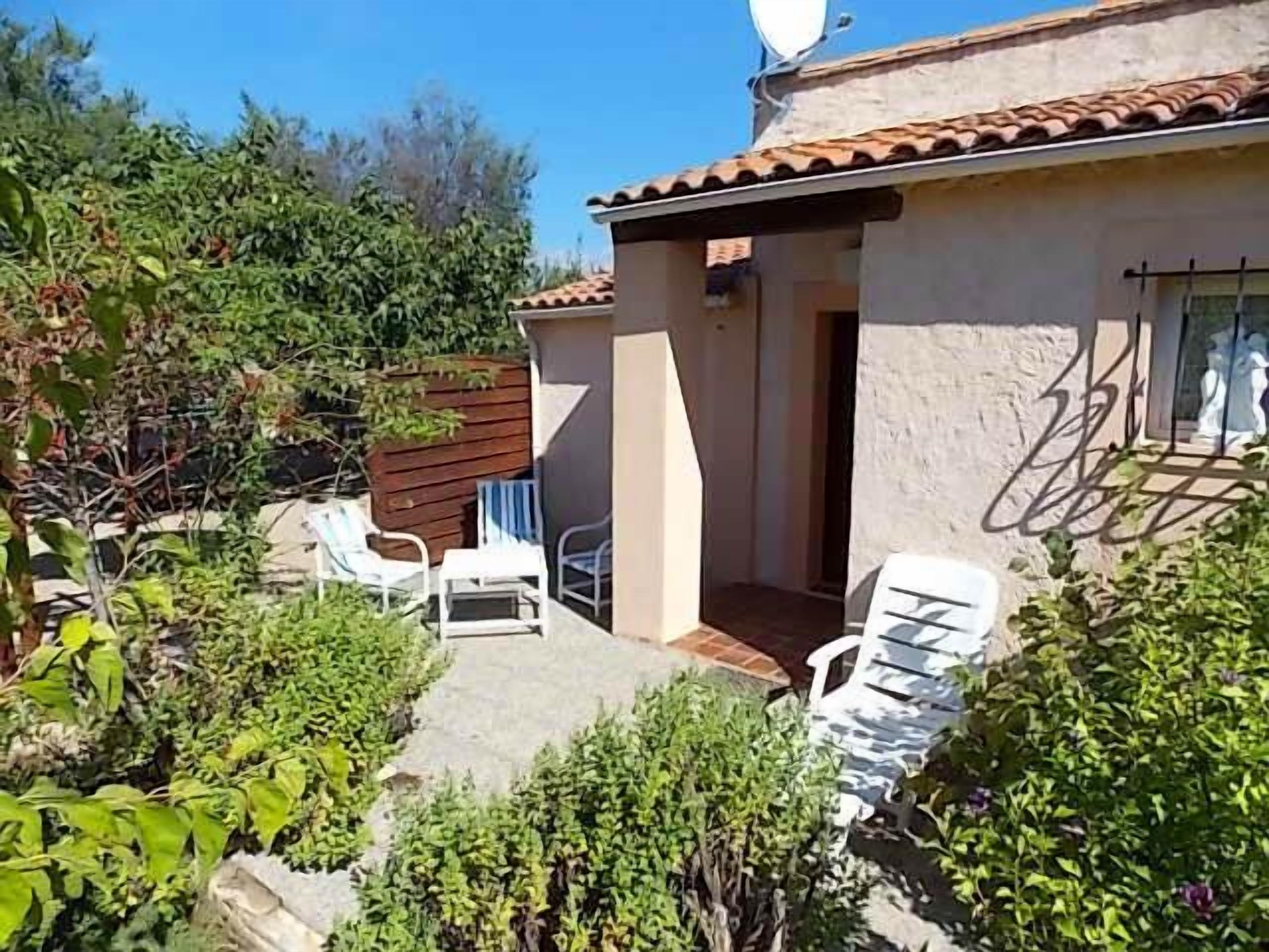 Una casa con patio, con sedie bianche e un tavolino.