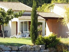 Relax in a traditional Mediterranean-style villa with a covered patio, outdoor seating, and beautifully manicured lawn.