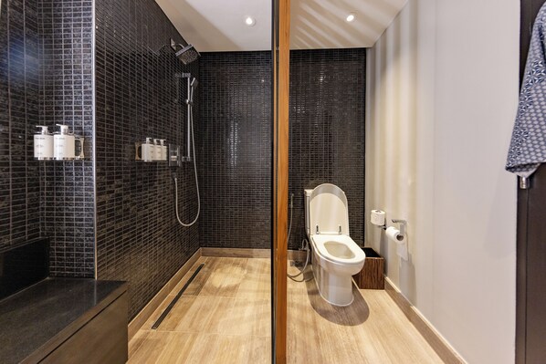 Un baño moderno con ducha, inodoro y tocador con artículos de aseo.