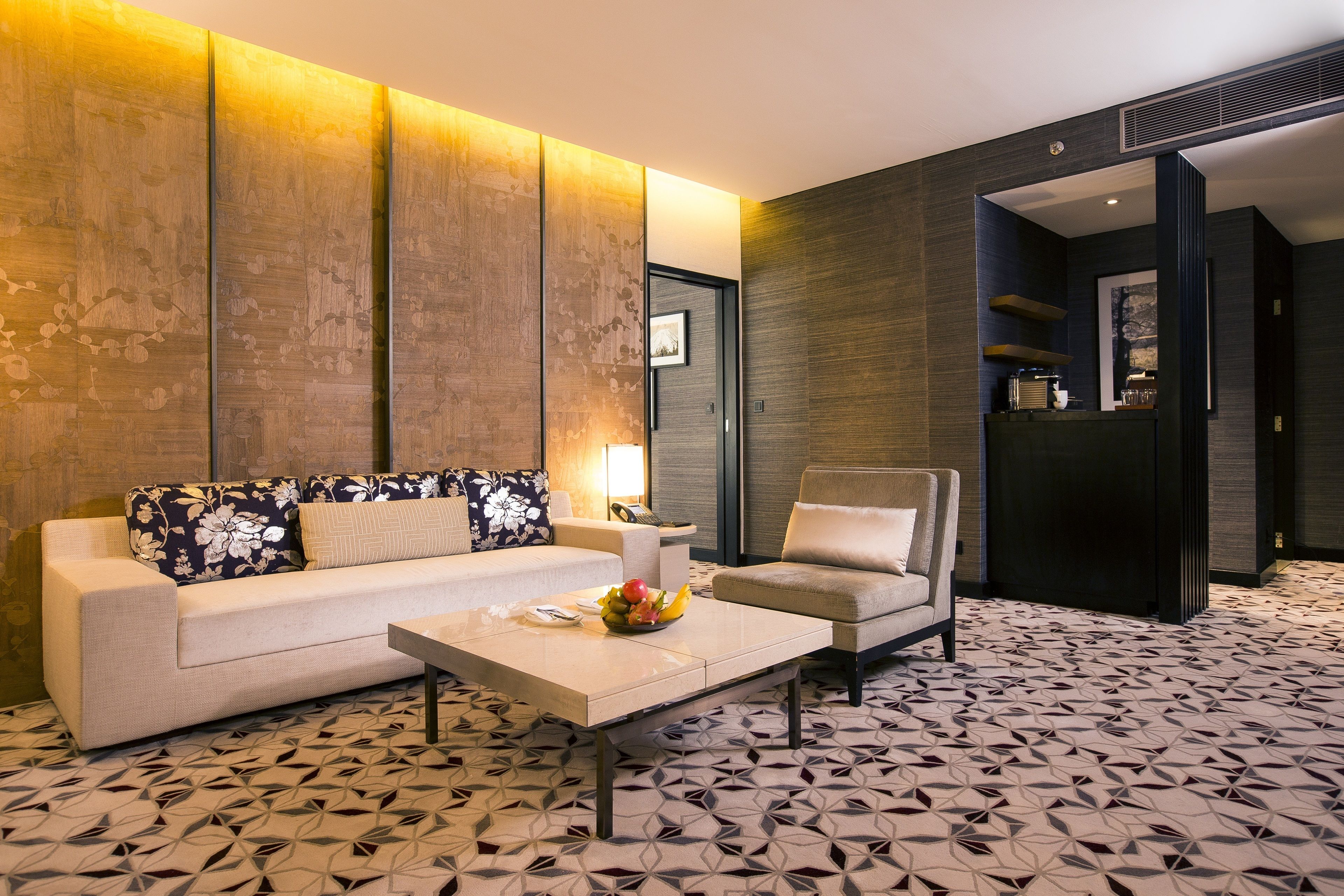 Una habitación de hotel moderna con sofá, sillón y mesa de centro.