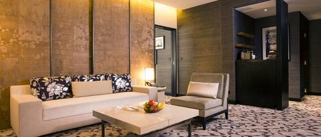 Una habitación de hotel moderna con sofá, sillón y mesa de centro.