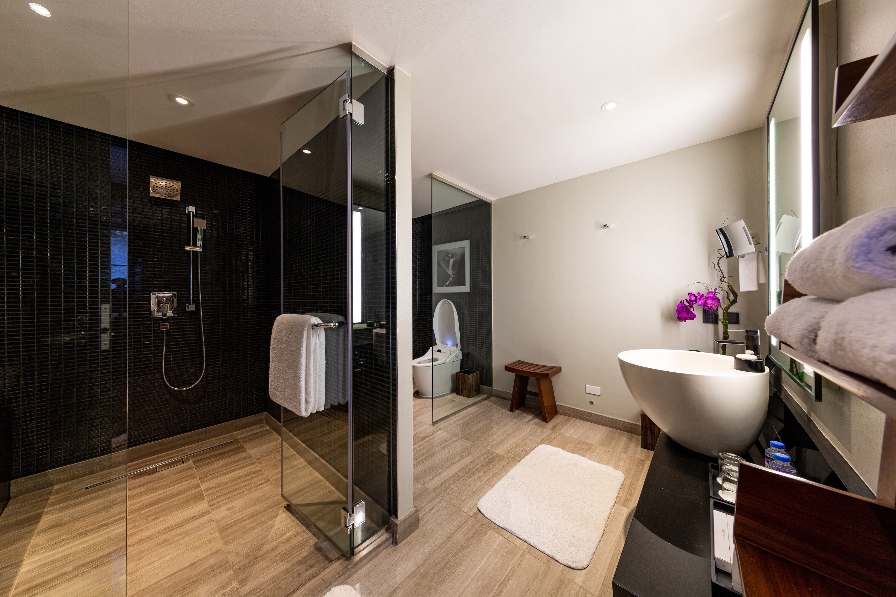 A modern bathroom with a glass-enclosed shower, a large white sink, and a wooden vanity.