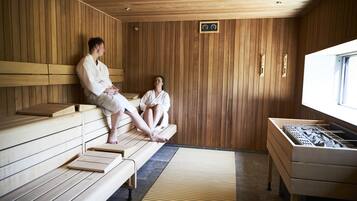 Una sala de sauna con bancos de madera y una bañera de hidromasaje de piedra.